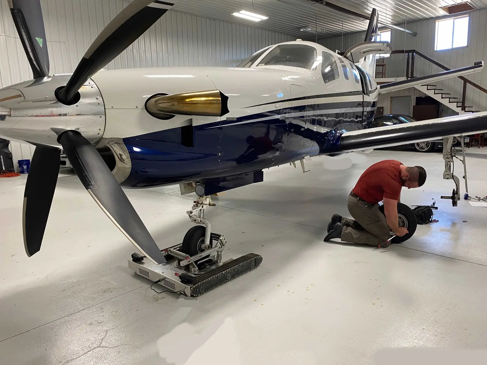 Technician working near a TBM aircraft in a maintenance hangar